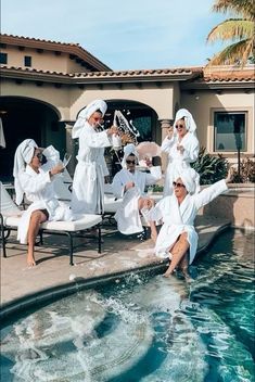 several people in white robes are sitting by the pool