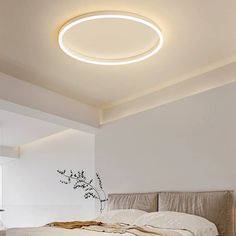 a white bed sitting under a round light in a bedroom