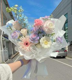 a person holding a bouquet of flowers in their hand on the street near a building