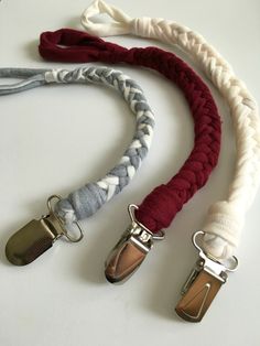 three lanyards are tied together on a white table with red and grey cords