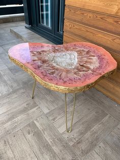 a pink and gold coffee table with a heart shaped decoration on it's side