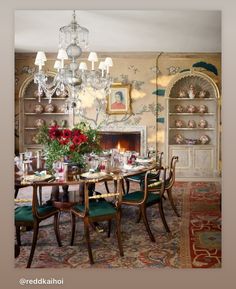 a dining room table with green chairs and a chandelier hanging from the ceiling