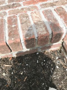 a cat is sitting on the ground next to a brick fire hydrant and mulch