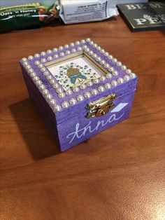 a wooden box with pearls on it sitting on a table next to some books and other items