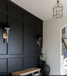 a black vase sitting on top of a wooden table next to a wall mounted clock