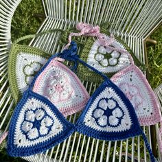 three crocheted bras sitting on top of a wicker chair in the grass