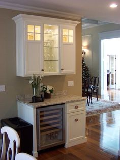 a kitchen with white cabinets and marble counter tops in the middle of hardwood flooring