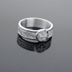 a wedding ring with the word love engraved on it's side, sitting on a reflective surface