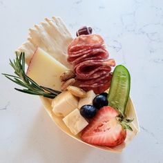 an assortment of cheeses, fruits and meats on a white marble countertop