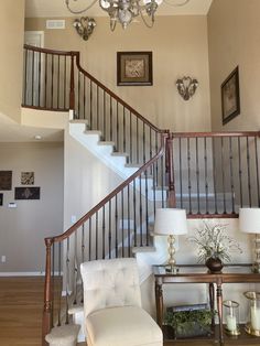 a white chair sitting under a chandelier in a living room next to a stair case