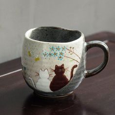 a coffee cup with a cat design painted on the inside and outside, sitting on a table