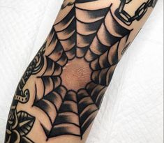 a black and white spider web tattoo on the arm with an ink pen in it