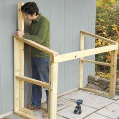 a man standing on the side of a building next to a wooden frame and hammer