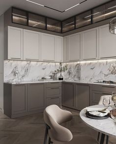 a large kitchen with marble counter tops and gray cabinets, along with a dining room table