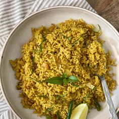 a white bowl filled with yellow rice and garnished with herbs