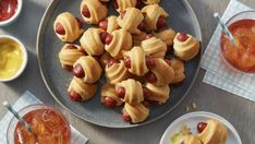 a plate full of hot dogs with ketchup and mustard on the side next to other dishes