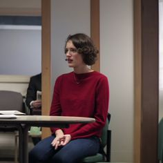 a woman sitting at a table talking to someone