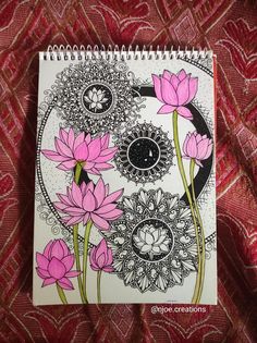 a spiral notebook with pink flowers on the cover and an intricate design in black ink