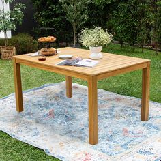 a wooden table sitting on top of a blue rug in the middle of a yard