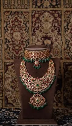 an elaborate necklace and earring set on display in front of a carpeted wall