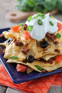 a blue plate topped with nachos covered in cheese and toppings on top of it