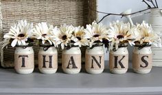 four mason jars with flowers in them sitting on a shelf