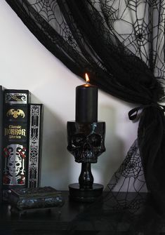 a candle that is sitting on top of a table next to books and a spider net