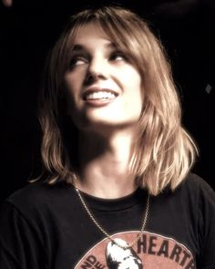 a woman with blonde hair wearing a black t - shirt and looking up into the sky