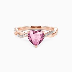 a pink heart shaped ring with diamonds on the sides and an arrow in the middle