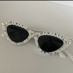 a pair of sunglasses with the words dirty thirty written on it and pearls attached to them