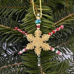 a snowflake ornament hanging from a christmas tree with beaded beads