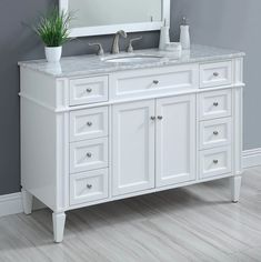 a white bathroom vanity with two sinks and a large mirror above it, in front of a gray wall