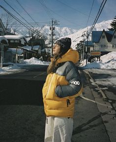 a woman standing in the street wearing a yellow jacket