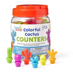 a jar filled with lots of colorful gummy bears next to cactus shaped plastic toys