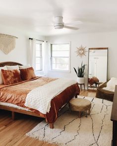 a bedroom with a bed, chair and rug on the hardwood floor in front of a large window