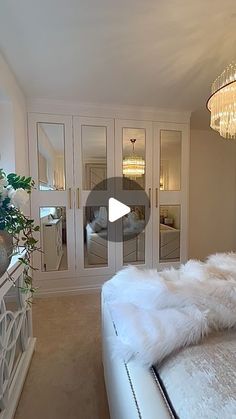 a large white bed sitting in a bedroom next to a tall glass doored closet