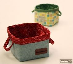 two small fabric storage baskets sitting on top of a white table next to each other