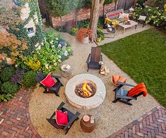 an outdoor fire pit in the middle of a yard with chairs and tables around it