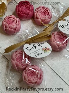 some pink flowers are in plastic bags on a white wooden table and there is a tag that says thank you