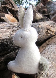 a white stuffed rabbit sitting on top of a wooden log