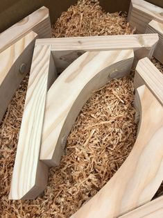 several pieces of wood are laying on some shredded up wood shavings in a box