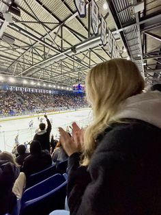 people are sitting in the stands at an ice hockey game, clapping and looking on