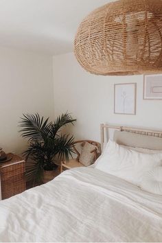 a bedroom with white linens, wicker furniture and a large basket hanging over the bed