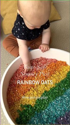 a baby sitting in front of a bowl filled with rainbow oats