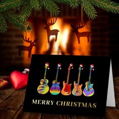 a christmas card with three guitars in front of a fireplace