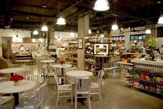 the inside of a grocery store with tables and chairs in front of shelves filled with condiments