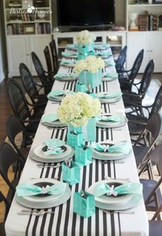 the table is set with black and white striped napkins, blue bows, and flowers