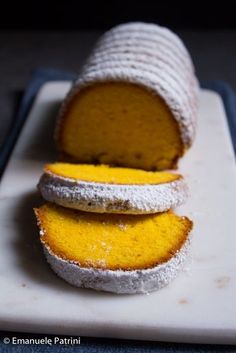 two pieces of cake sitting on top of a cutting board with powdered sugar around them