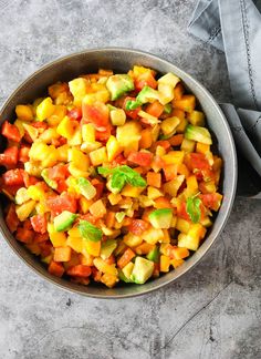 a bowl filled with chopped vegetables on top of a gray countertop next to a napkin