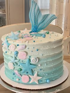 a blue and white cake decorated with stars, seashells and seahorses